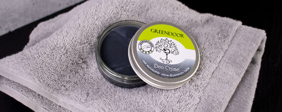GREENDOOR Fußcreme auf grauem Handtuch Dose mit GREENDOOR Fußcreme, geöffnet auf einem grauen Handtuch