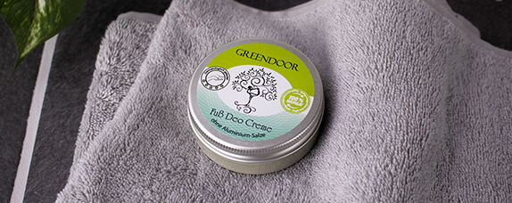 geschlossene Dose Greendoor Deo Creme für Füße in altem Design, Dose liegt auf grauem Frottee Tuch