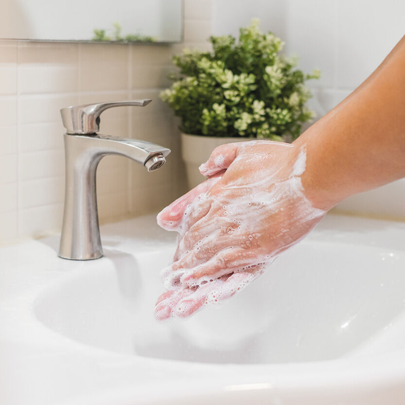 Bildmaterial_Basisch Ein Waschbecken, über dem zwei Hände beim Händewaschen zu sehen sind