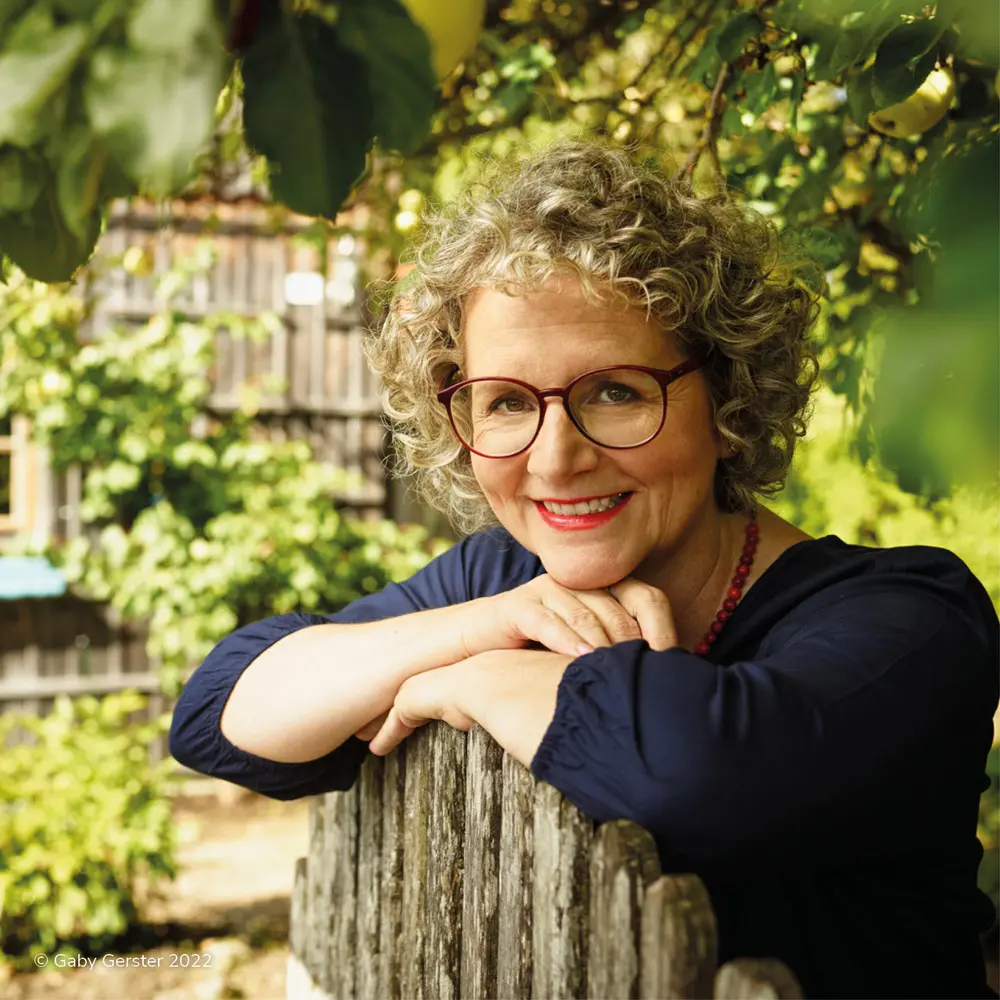 Lächelnde Frau mittleren Alters, die eine Brille trägt in einem grünen Garten